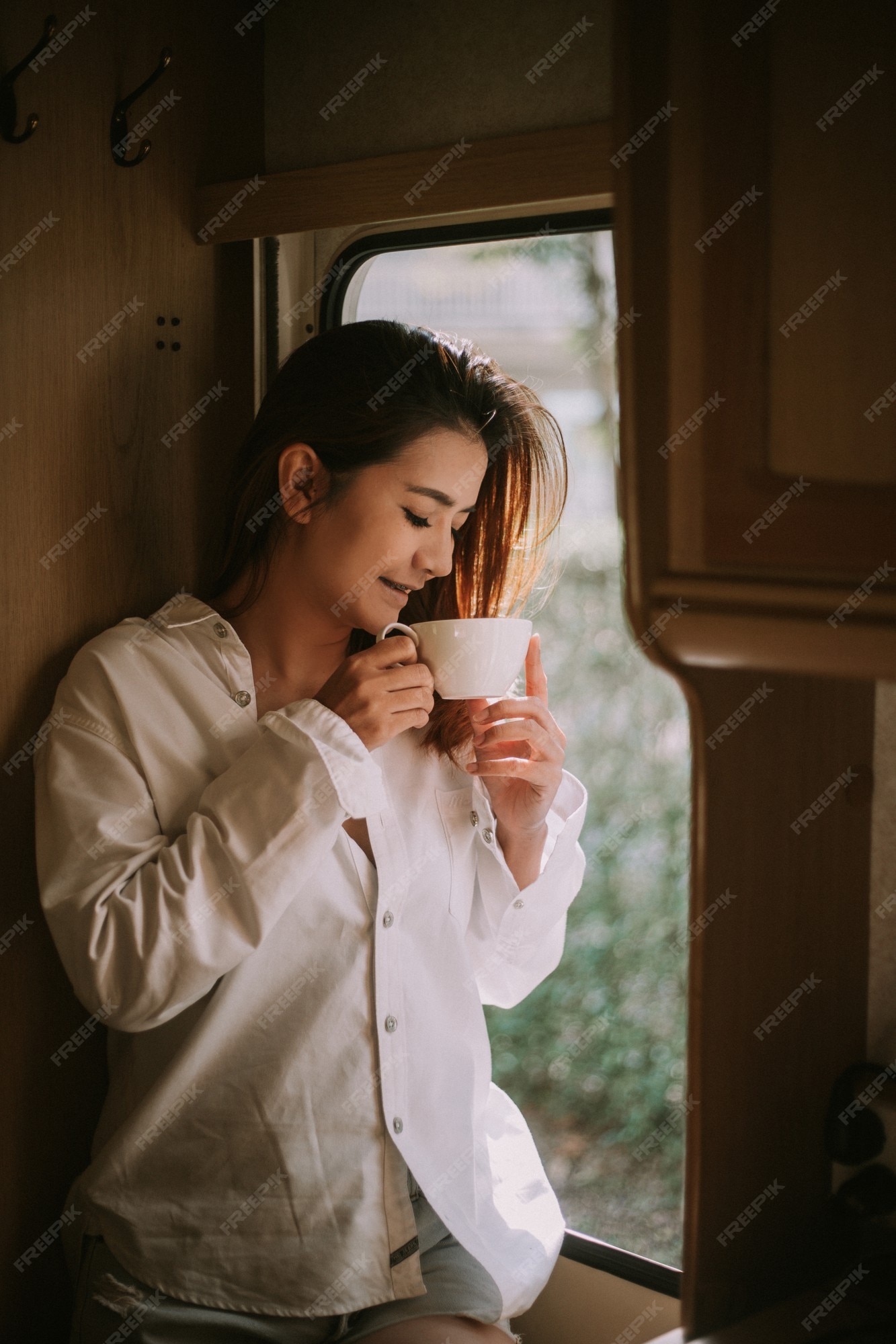 Premium Photo | Beautiful blonde woman next to a window, wearing men shirt drinking coffee