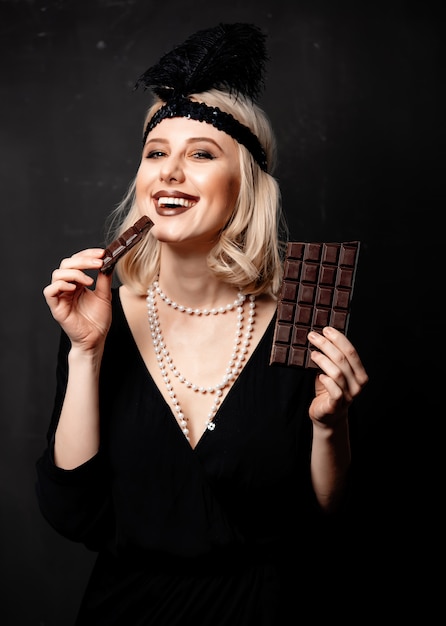 Beautiful blonde woman in twenties years clothes with chocolate slice