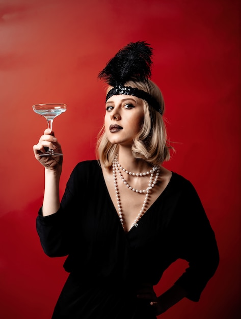 Photo beautiful blonde woman in twenties years clothes with cocktail on dark background