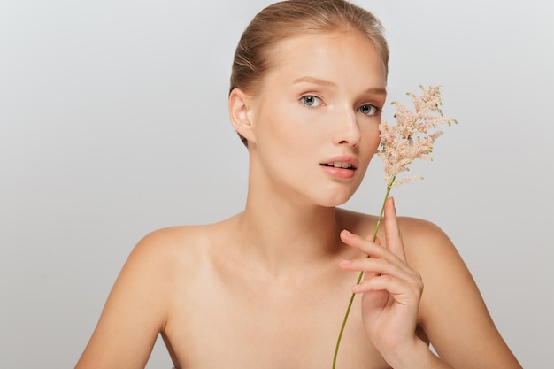 Beautiful blonde woman with perfect skin and a floral branch