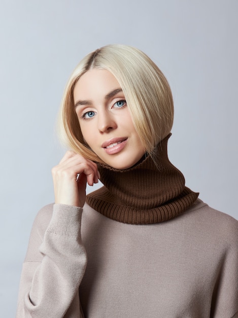 Beautiful blonde woman with a Snood Scarf around her neck. Girl in spring clothes, warm sweater