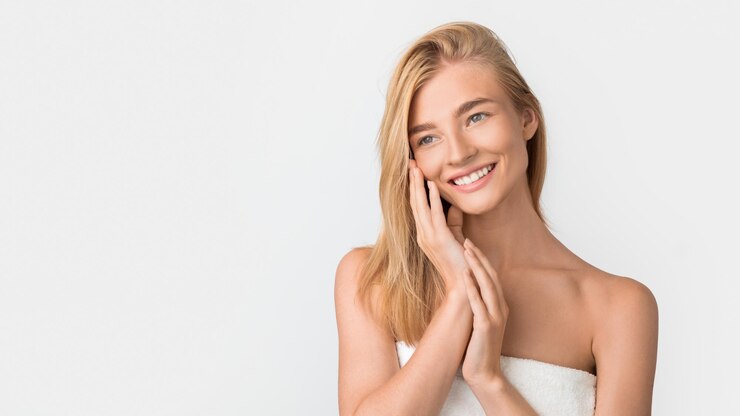 Photo beautiful blonde woman wrapped in towel touches face white studio