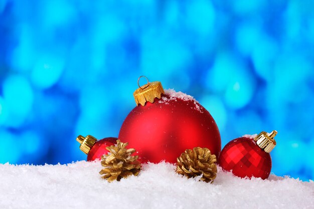 青い背景の上の雪の上の美しい青いクリスマスボールとコーン
