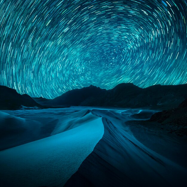 Beautiful blue night desert and dune on star trail background