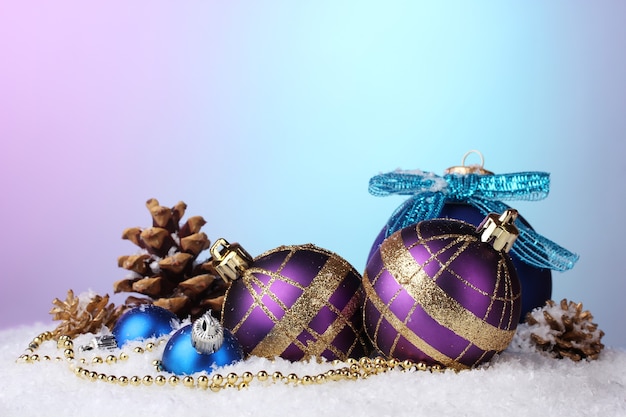 雪の上の美しい青と紫のクリスマスボールとコーン
