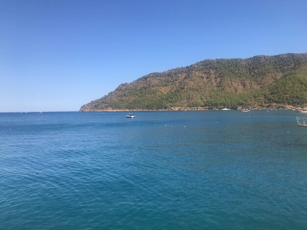 Beautiful blue sea and small ships against the backdrop of high mountains in a warm tourist