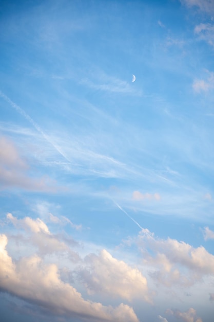 Bel cielo azzurro con nuvole e luna nascente alla luce del giorno