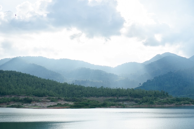 Beautiful blue sky with sunlight shining through white clouds over lake and mountain.