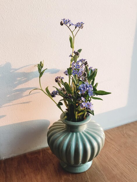 Beautiful blue spring flowers in vase on windowsill in evening sunlight Forget me nots