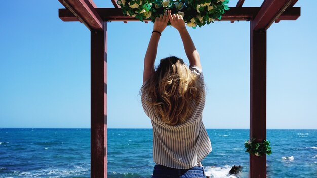 Beautiful bohemian styled and tanned girl at the beach against the backdrop of sea waves