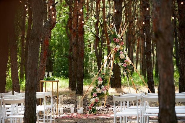 Beautiful bohemian tipi arch decoration on outdoor wedding ceremony venue in pine forest with cones