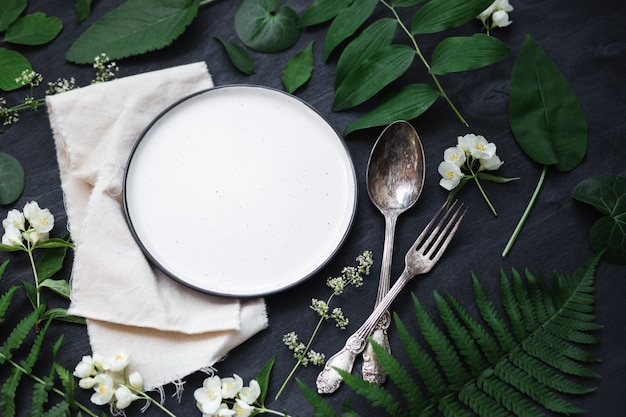 Foto bellissimo tavolo primaverile boho allestito mockup con decorazioni di fiori e piante selvatiche. foto vista dall'alto piatta alla moda.