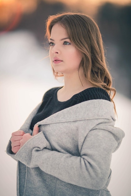 Beautiful Bosnian Caucasian woman in gray coat looking at the camera with serious face in snow