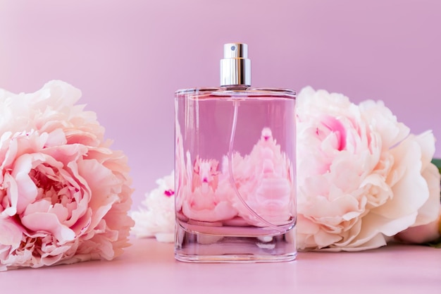 Beautiful bottle of women\'s perfume on a pink background with a\
chic flower of fragrant peony front view template for perfume and\
toilet water