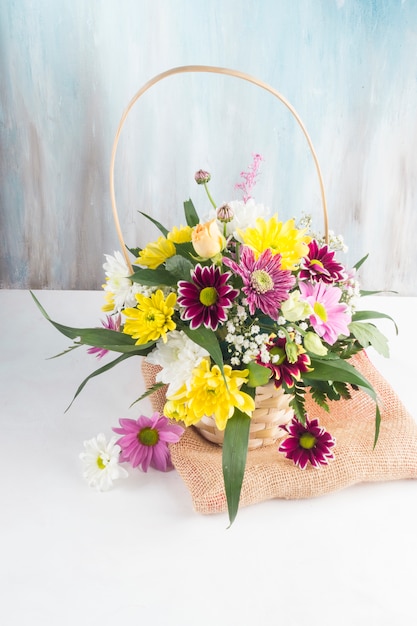 Beautiful bouquet in basket placed on burlap