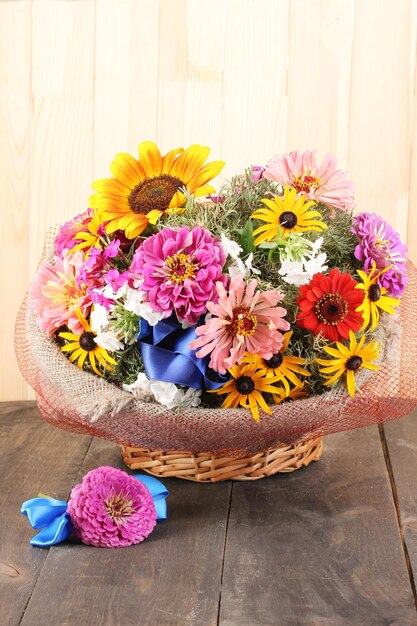 Beautiful bouquet of bright flowers in sacking on wooden background