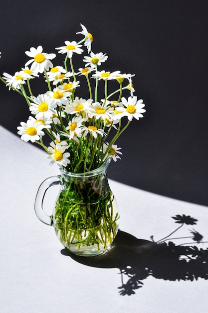 Beautiful bouquet of daisies in glass vase grey table