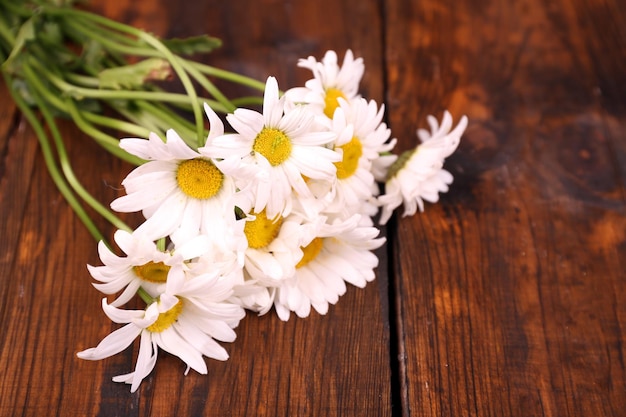 Beautiful bouquet of daisies on wooden background