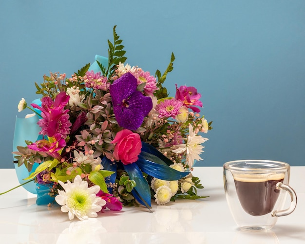 一杯のコーヒーとさまざまな花の美しい花束