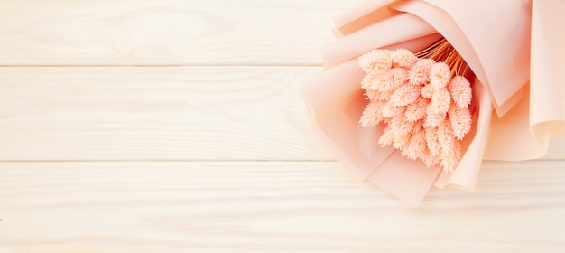 木製の白い背景にドライのピンクの花の美しい花束。