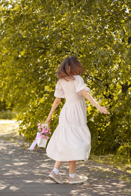 거리를 걷는 아름다운 소녀의 손에 든 상자에 담긴 아름다운 꽃다발