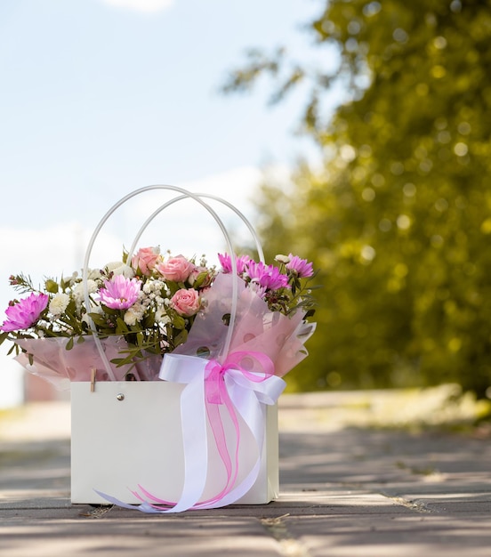 通りを歩く美しい少女の手にある箱の中の花の美しい花束