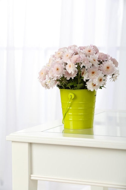 Beautiful bouquet of flowers in bucket on window background