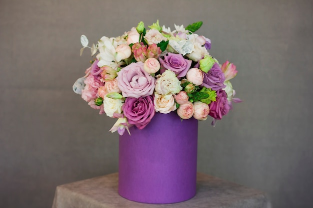 The beautiful bouquet of flowers in purple box on gray background