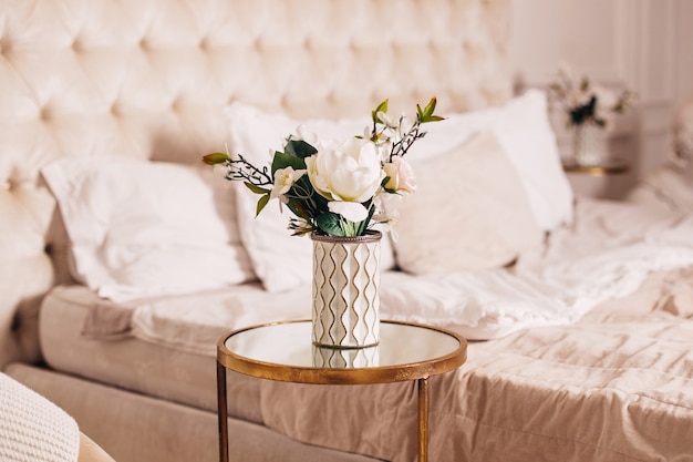 Beautiful bouquet of flowers in vase on bedroom background