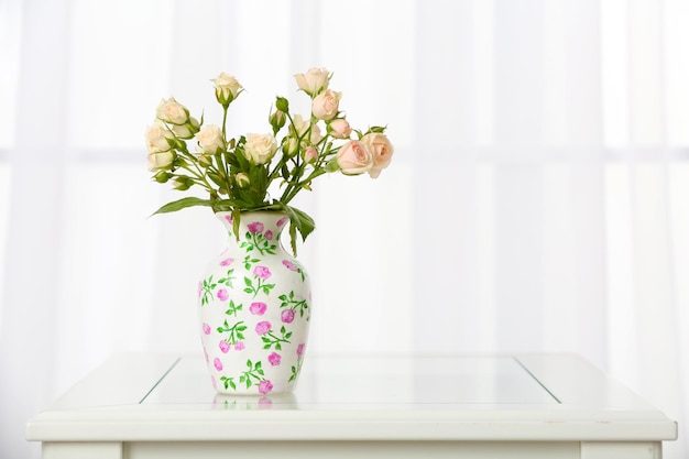 Beautiful bouquet of flowers in vase on window background