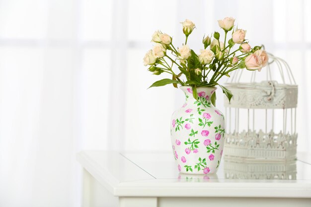 Beautiful bouquet of flowers in vase on window background