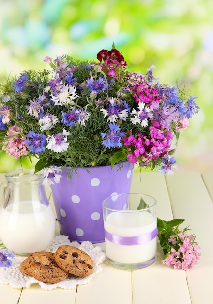 写真 自然の背景の木製のテーブルにバケツで美しい花束