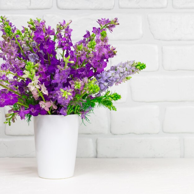 Beautiful bouquet of lilac purple flowers in a white vase on a white background Mothers Day Greeting card Place for an inscription