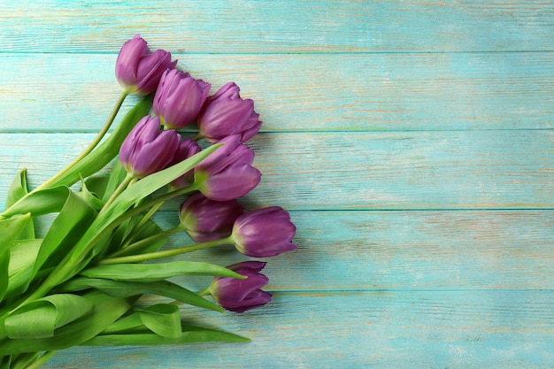 Beautiful bouquet of lilac tulips on color wooden background