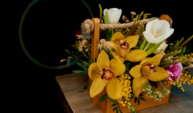손잡이가 있는 나무 상자에 노란색과 흰색 꽃의 아름다운 꽃다발. 고품질 사진