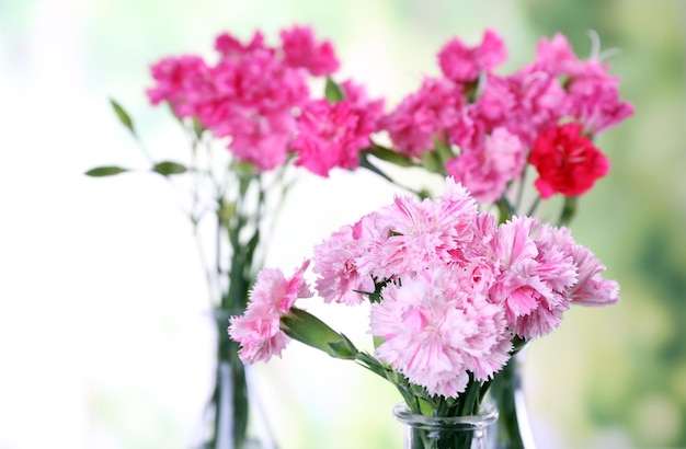 Beautiful bouquet of pink carnation in vases on bright background