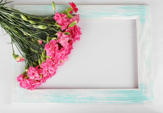 白で隔離の木製フレームとピンクのカーネーションの美しい花束
