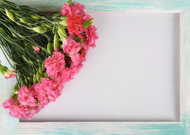 白で隔離の木製フレームとピンクのカーネーションの美しい花束