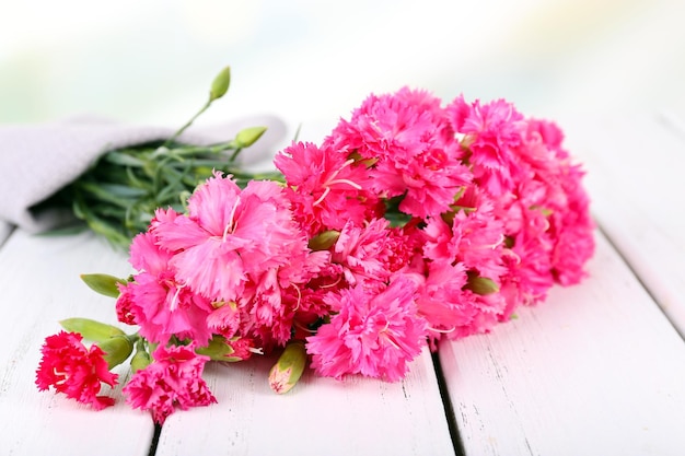 Beautiful bouquet of pink carnation on wooden table close up