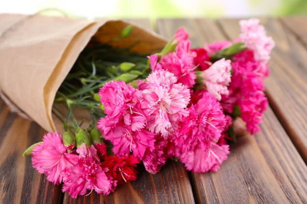 Beautiful bouquet of pink carnation on wooden table close up