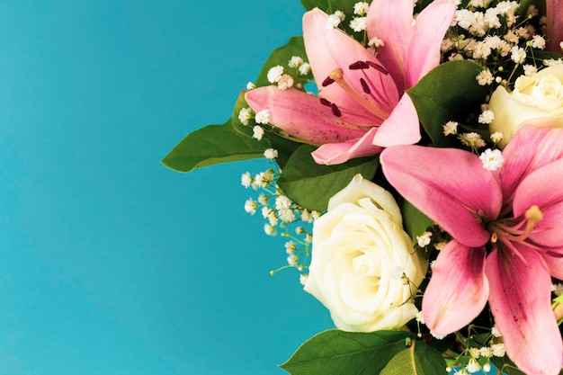 A beautiful bouquet of pink lilies and white roses on a blue background in vintage processing Place for text