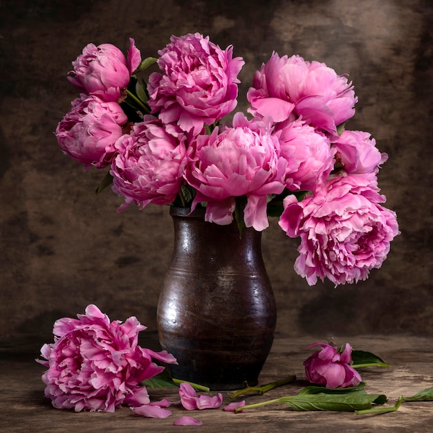 Beautiful bouquet of pink peonies in vase on a wooden table