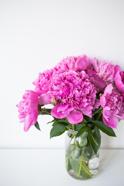 Beautiful bouquet of pink peony flowers in a vase on a white table Flower surprise on March 8