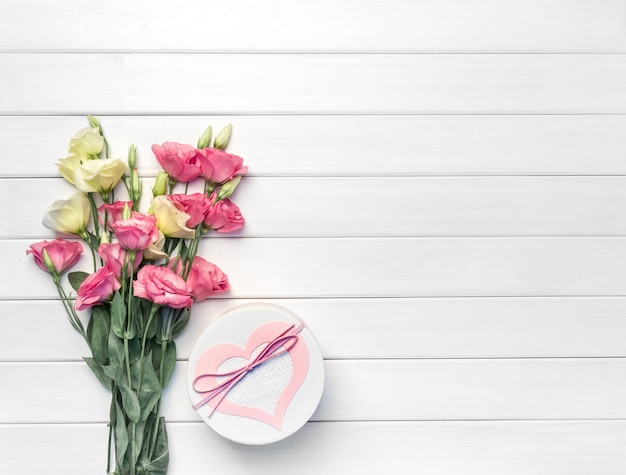 Beautiful bouquet of pink, purple, yellow eustoma flowers and handmade gift box on white wooden