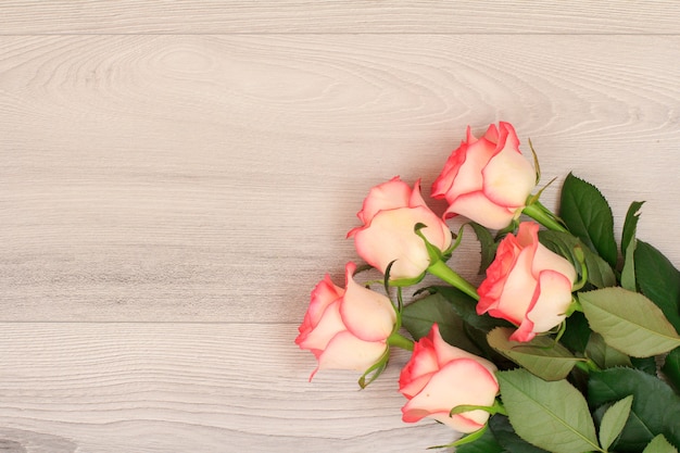 Beautiful bouquet of pink roses on gray wooden background. Top view with copy space.