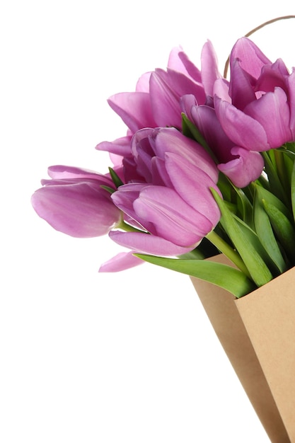 Beautiful bouquet of purple tulips in paper bag, isolated on white