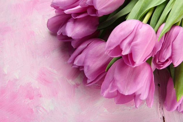 Beautiful bouquet of purple tulips on pink wooden background