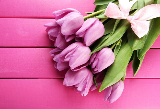 Beautiful bouquet of purple tulips on pink wooden background