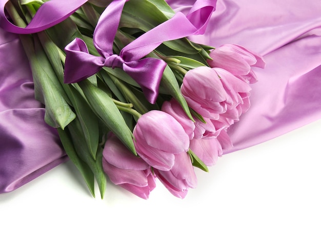 Beautiful bouquet of purple tulips on satin cloth, isolated on white