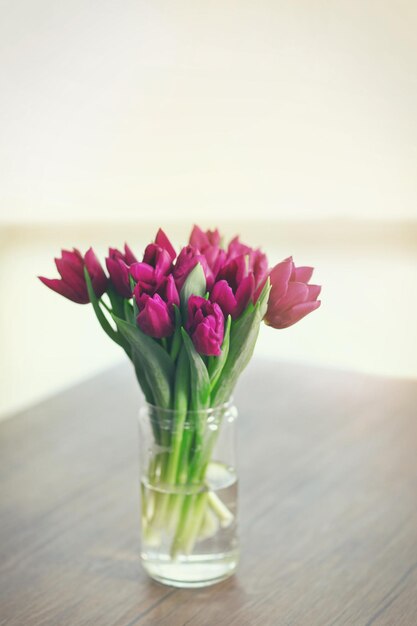 Beautiful bouquet of purple tulips on wooden table at living room